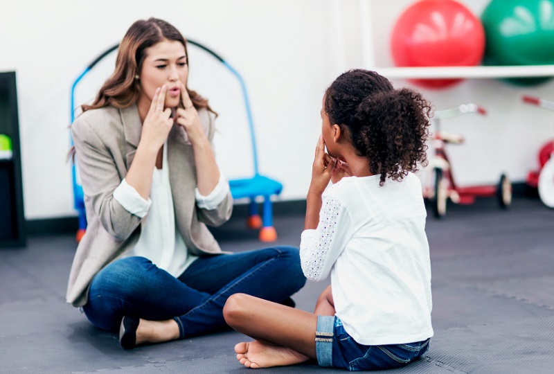  A speech-language pathologist interacts with a child during ASD speech therapy.